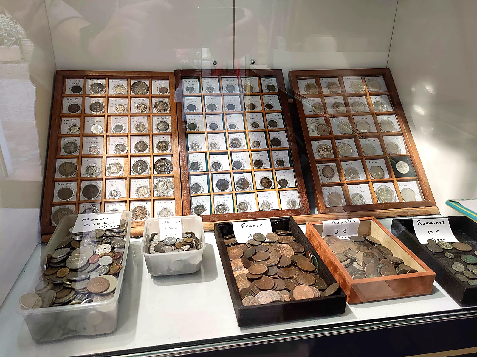 Plateaux de monnaies royales, romaines et du monde en vitrine, et bacs de monnaies françaises à petits prix